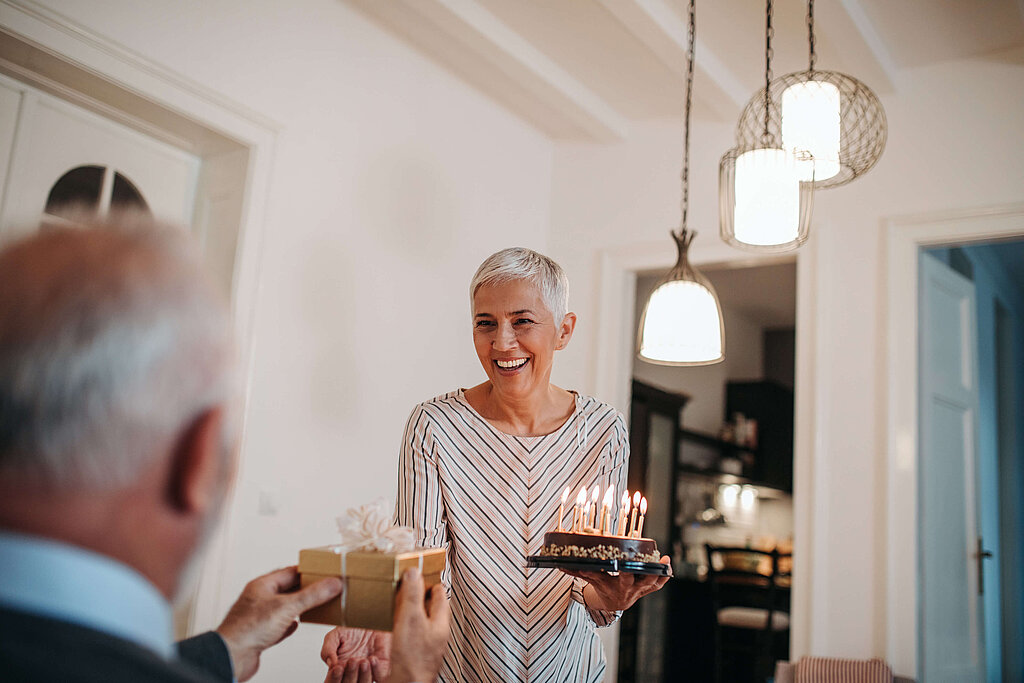 Frau mit Kuchen, Mann hält Geschenk in der Hand