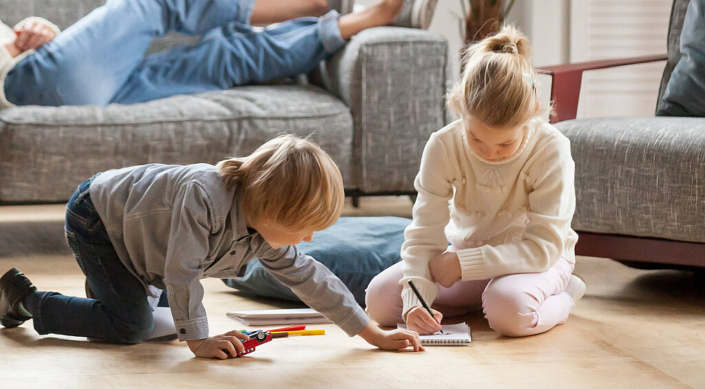 Personen sitzen und liegen auf Couch vor Ihnen spielen Kinder