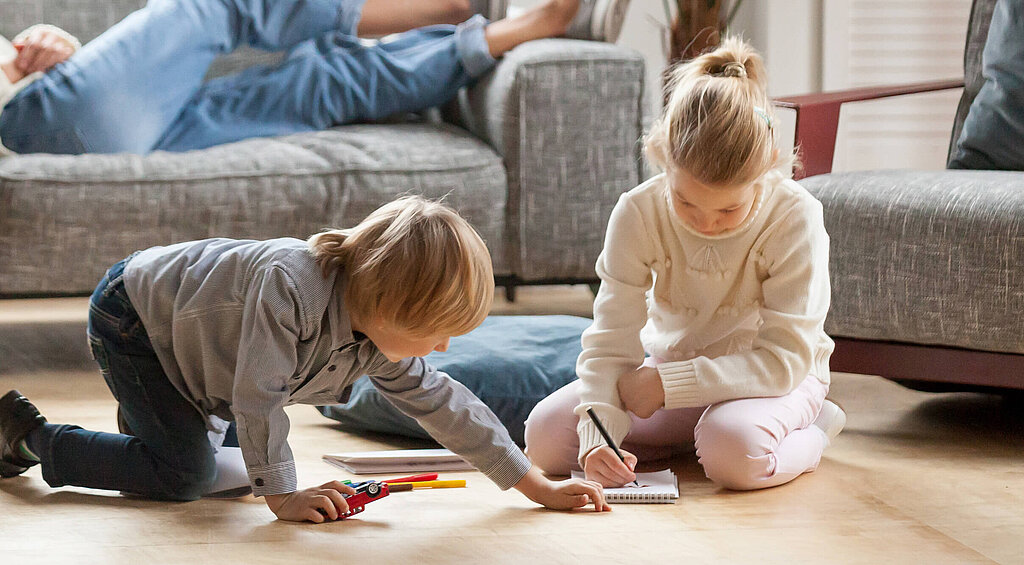 Personen sitzen und liegen auf Couch vor Ihnen spielen Kinder