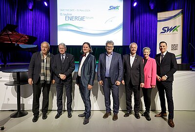 Personen stehen nebeneinander vor Bühne bei Energieforum