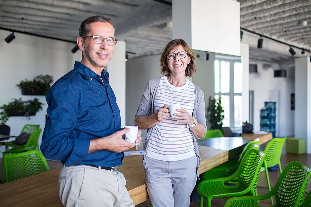 Mann und Frau im Büro mit Tasse in der Hand 