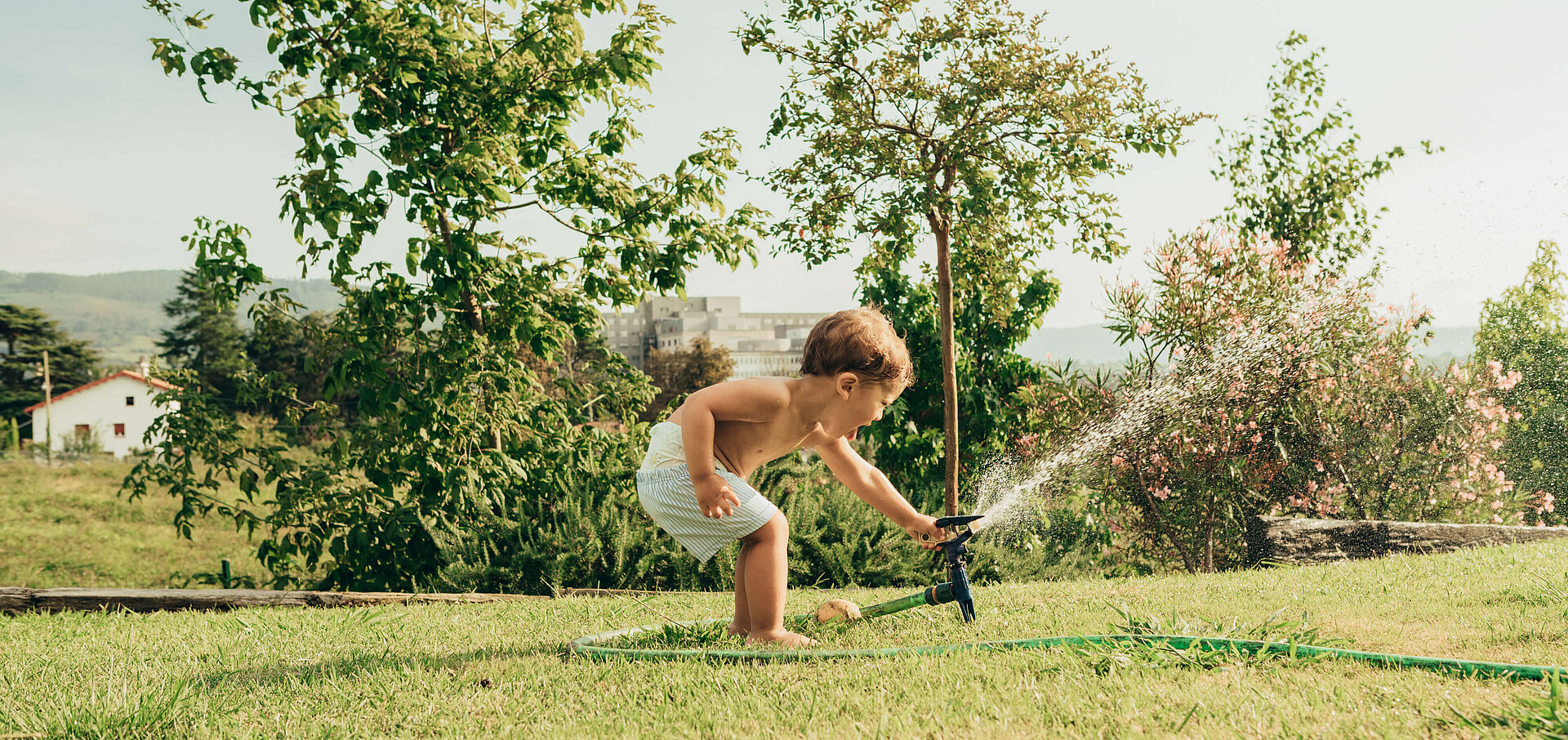 Junge im Garten mit Wassersprengler