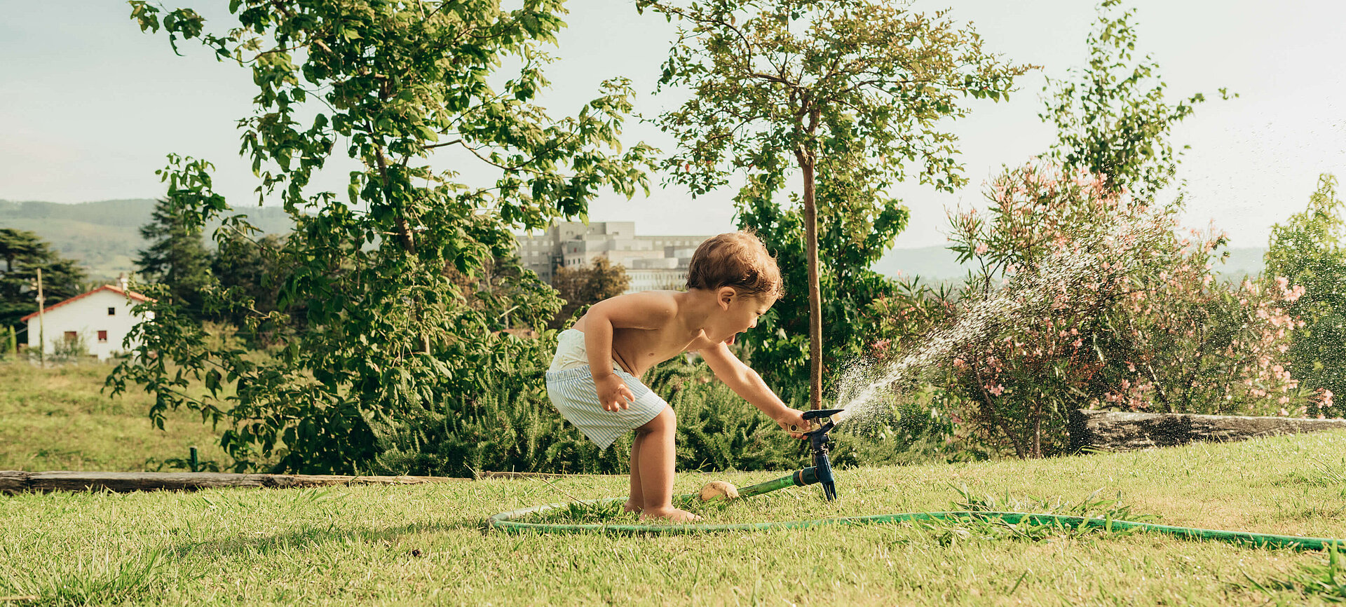 Junge im Garten mit Wassersprengler