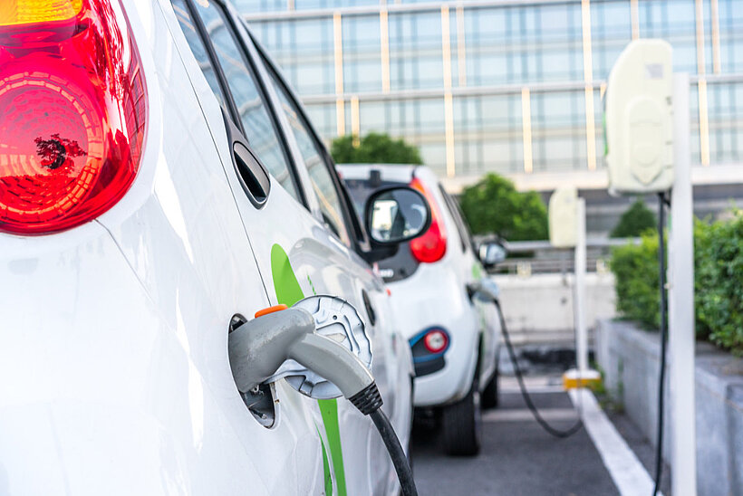 Autos am Laden an öffentlichen Ladestationen vor Gebäude