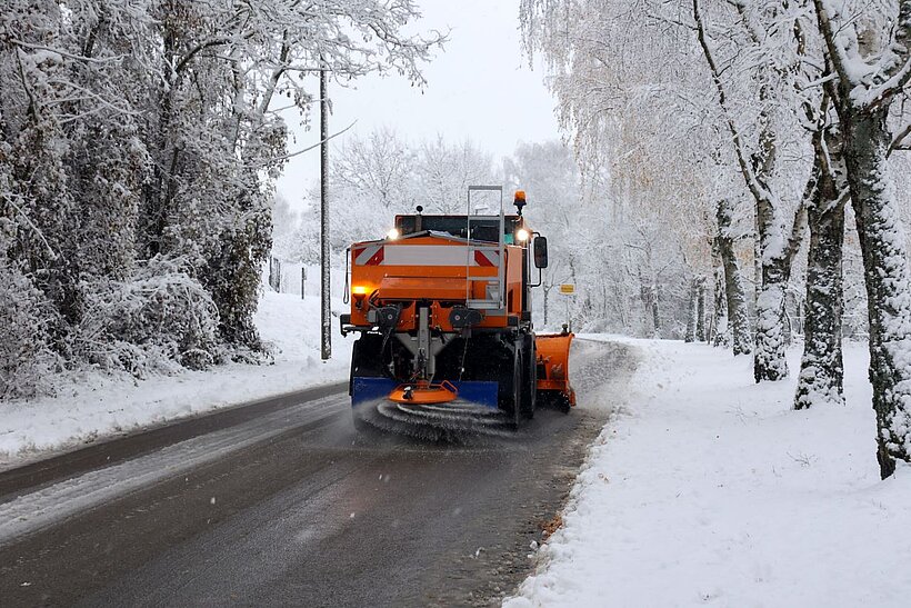 Schneepflug fährt durch verschneite Landschaft