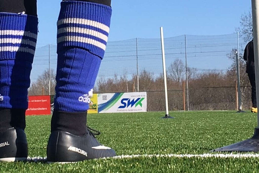 Person in Fußballschuhen und Stollen Fußballplatz Training Alex Roos Fußballschule Kaiserslautern SWK-Banner im Hintergrund